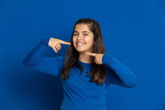 Preteen Mädchen mit blauem Trikot gestikuliert über blaue Wand