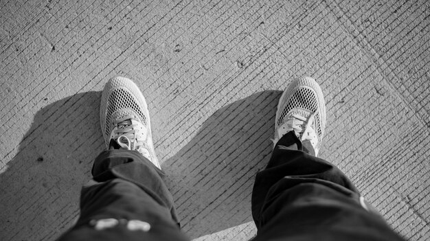 Foto preto e branco de de cima de colheita irreconhecível homem em roupas casuais e tênis de pé