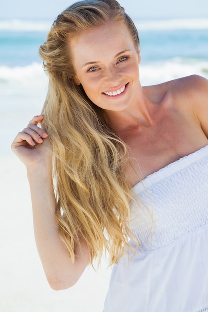 Pretty blonde despreocupado sorrindo para a câmera na praia