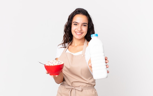 Pretty chef hispana mujer sosteniendo un tazón de desayuno con leche