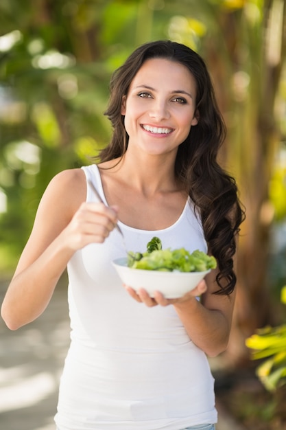 Pretty morena comendo tigela de salada