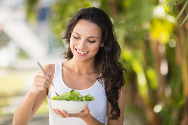 Pretty morena comendo tigela de salada