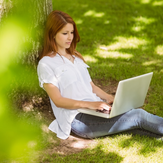 Pretty redhead digitando em seu laptop