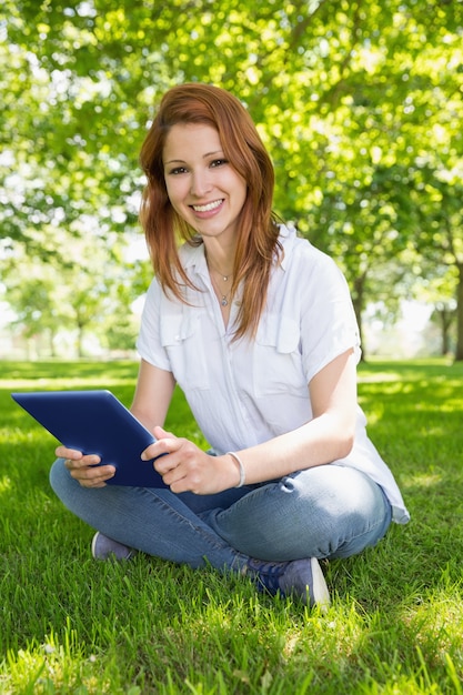 Pretty redhead usando seu tablet pc no parque