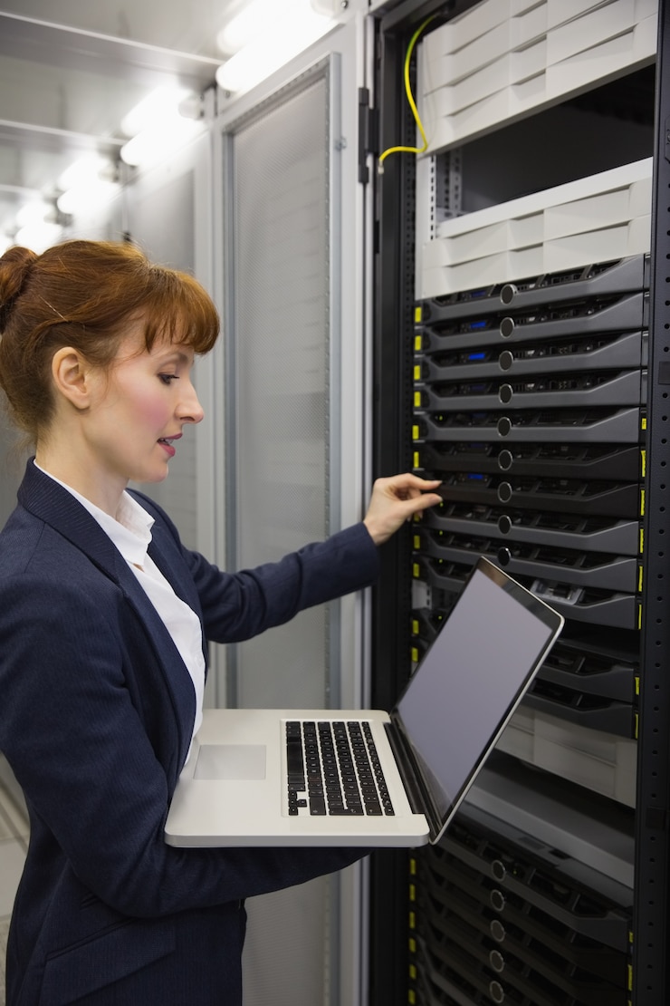 Foto pretty technician usando o laptop enquanto trabalha em servidores