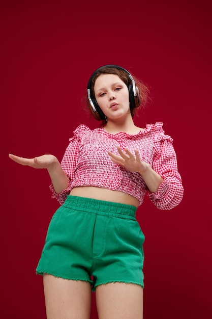 Pretty Woman en blusa rosa y shorts verdes con auriculares escuchando música