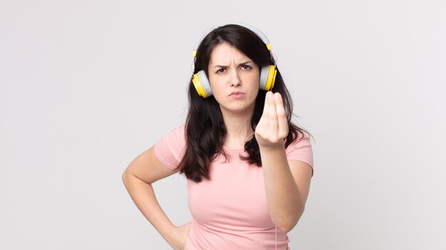 Pretty Woman haciendo capice o gesto de dinero, diciéndole que pague escuchando música con auriculares