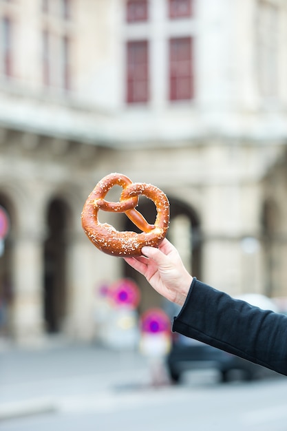 Pretzel salado en manos de un hombre en el fondo de la Ópera de Viena