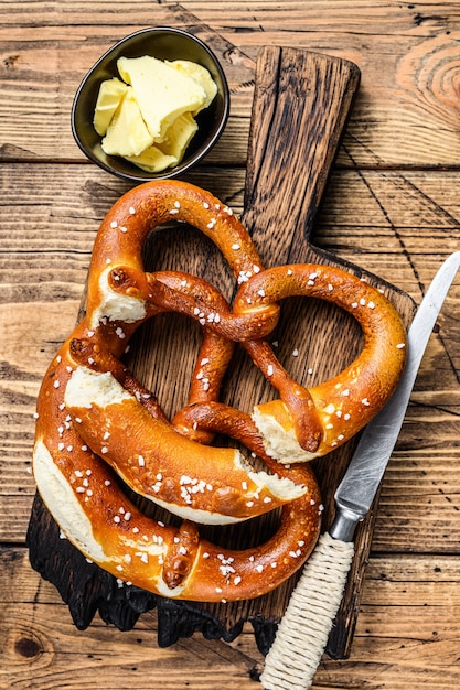 Pretzels assados com sal marinho em uma tábua de madeira rústica. Fundo de madeira. Vista do topo.