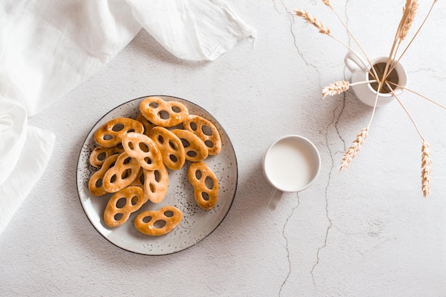 Pretzels bávaros en un plato y una taza de leche en la mesa. Merienda para comida rápida. Vista superior