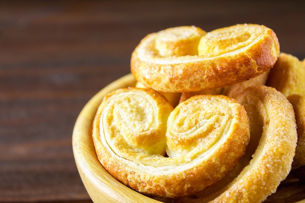 Pretzels doces feitos de massa folhada em uma tigela sobre uma mesa de madeira