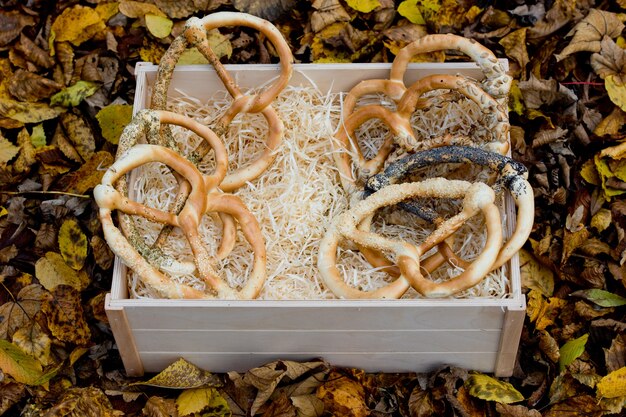 Pretzels frescos variados em uma caixa de madeira com fundo de folhagem amarela de outono.