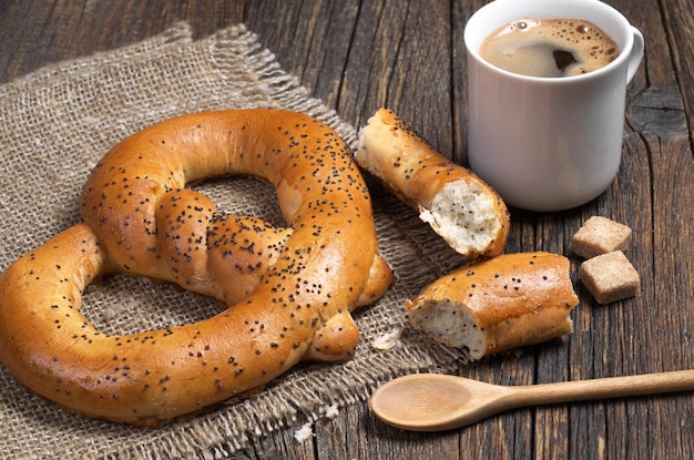 Pretzels macios com xícara de café quente no café da manhã em um tecido áspero localizado em uma velha mesa de madeira