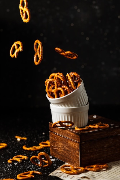 Pretzels con sal caen de una taza blanca.