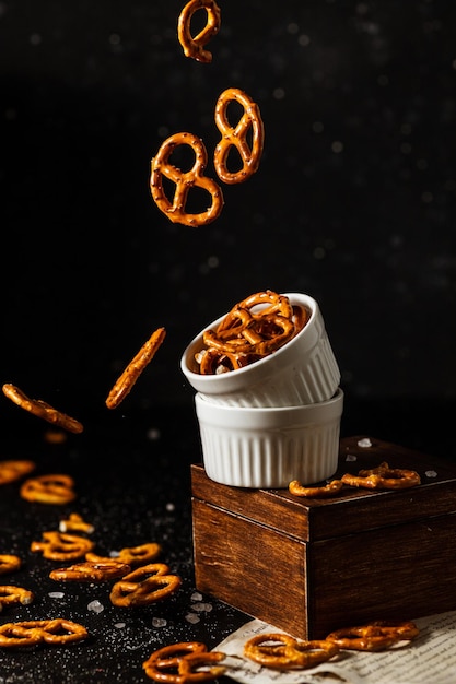 Pretzels con sal caen de una taza blanca.