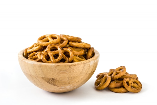 Pretzels en el tazón de madera aislado en la superficie blanca.