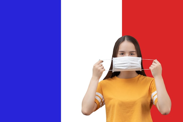 Prevención del coronavirus en Francia Niña se pone una máscara médica antibacteriana sobre un fondo de bandera con espacio de copia