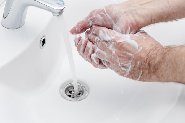 Prevención de coronavirus lavándose las manos con jabón antibacteriano en el lavabo del baño.