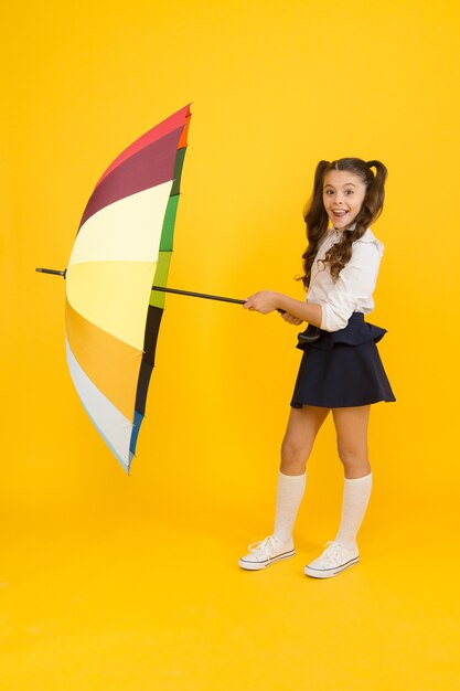 Previsão do tempo de outono. Acessório de moda. Escudo de proteção guarda-chuva. Menina com guarda-chuva. Caminhadas em dias chuvosos. Infância feliz. Hora da Escola. Estilo arco-íris. Vida colorida. Colegial feliz com guarda-chuva.