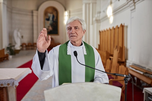 Priester liest Bibel im Mikrofon in der Kirche