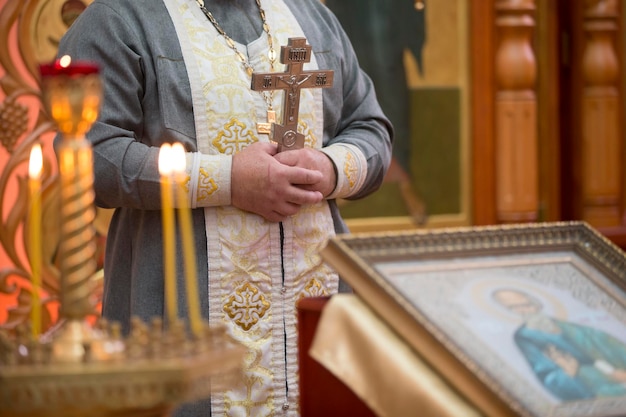 Priester mit einem Kreuz auf dem Hintergrund der Ikone