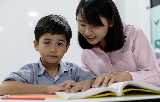 Primäre asiatische Schüler. Asiatischer Schüler in einheitlichem Lesebuch in der Schule während des Unterrichts