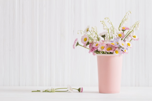 Primavera flores em um vaso no fundo branco de madeira