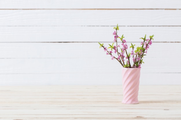 Primavera flores em um vaso no fundo branco de madeira