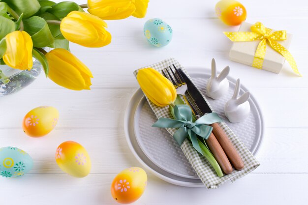 Primavera fondo de Pascua para el menú. Decoración de huevos de Pascua, conejito, servilleta de lino en plato y cubiertos de cocina en mesa de madera blanca. Lay Flat