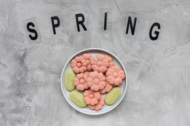 PRIMAVERA galletas de palabra y flor en un plato sobre un gris