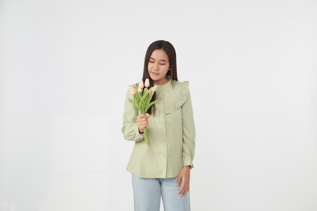 Primavera Hermosa niña alegre sonriendo y sosteniendo un ramo de flores de tulipán. Joven mujer asiática feliz.