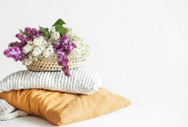 La primavera lila florece en el interior de la habitación con almohadas decorativas en una mesa de luz.