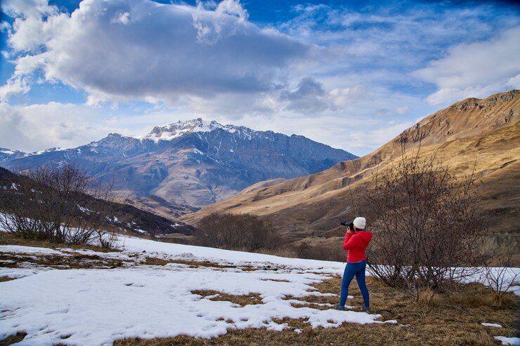 Primavera en las montañas, la nieve se derrite. La fotógrafa de la niña dispara el paisaje.