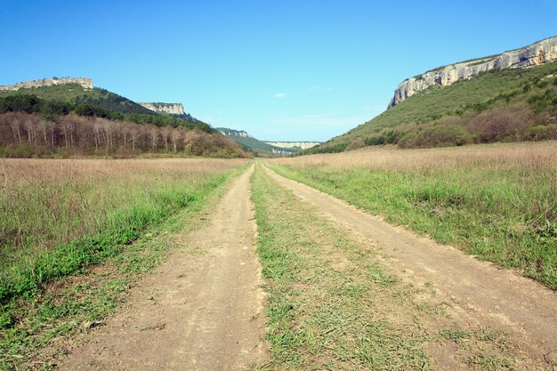 Primavera paisaje montañoso de Crimea y caminos rurales en el valle (Mangup Kale - fortaleza histórica y asentamiento de cuevas antiguas en Crimea, Ucrania)