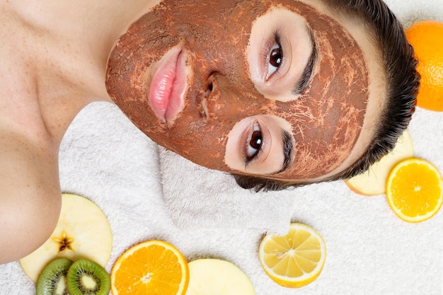 Foto primavera saúde pessoas juventude e conceito de beleza máscaras faciais naturais de frutas caseiras frutas frescas spa mulher aplicando máscara de limpeza facial tratamentos de beleza