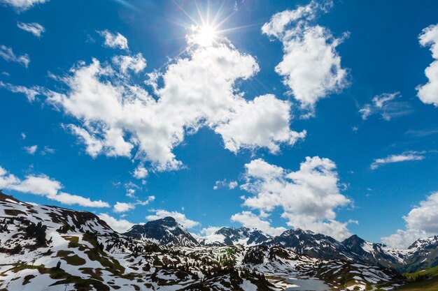 Foto primavera soleada vista a la montaña de los alpes desde hochtannbergpass con sol y nubes en el cielo azul (warth, vorarlberg, austria)