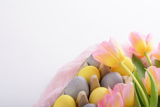 Primavera tierna composición de Pascua de huevos pascuales tulipanes rosas sobre fondo blanco con espacio de copia