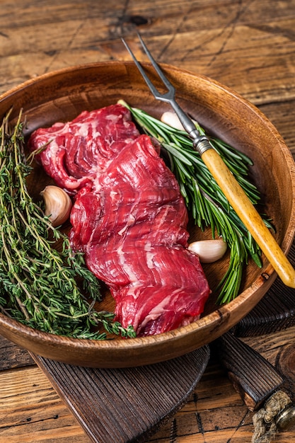 Prime Raw Machetenrock Rindersteak in Holzplatte mit Kräutern. hölzerner Hintergrund. Draufsicht.