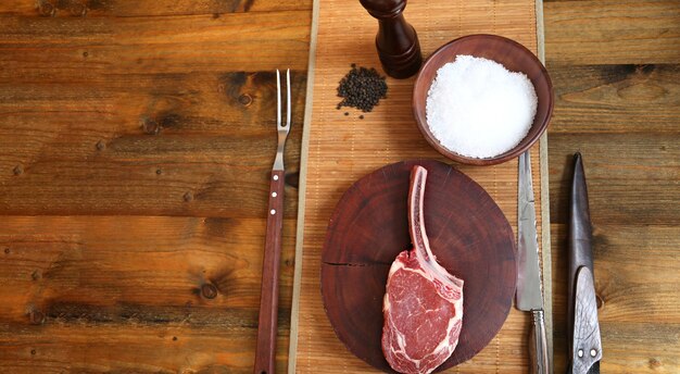 Prime Rib Raw Rib Eye Steak mit Knochen zum Grillen auf Holzhintergrund