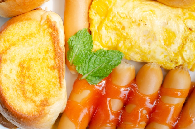 Primeiro café da manhã com salsicha, pão, ovo na chapa branca no tempo da manhã