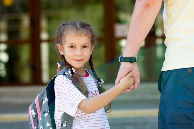 Primeiro dia na escola. Papai lidera uma garotinha na primeira série. De volta à escola.