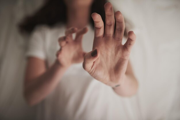 Primeiro não faça mal foto de alto ângulo de uma jovem não identificável segurando as mãos em um gesto defensivo enquanto estava deitada na cama