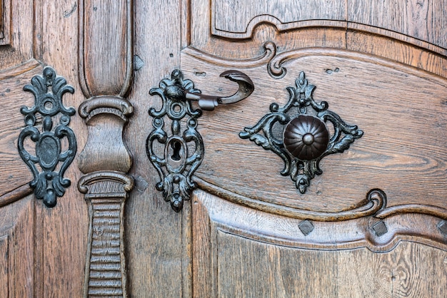 Primeiro plano da porta de madeira velha com punho do ferro. Punho oxidado velho da porta na porta de madeira.