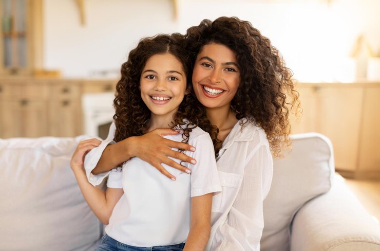 Foto primeiro retrato conceitual de família de mãe e filha felizes abraçadas e sorrindo para a câmera sentadas