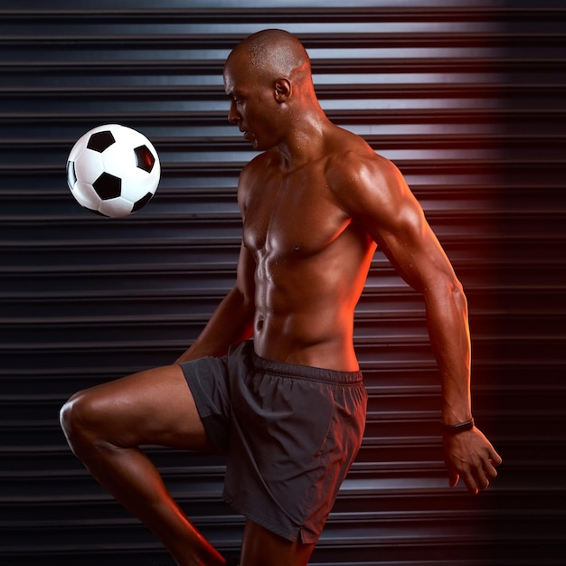 Primeiro toque perfeito Foto de estúdio de um jovem atlético jogando com uma bola de futebol contra um fundo cinza