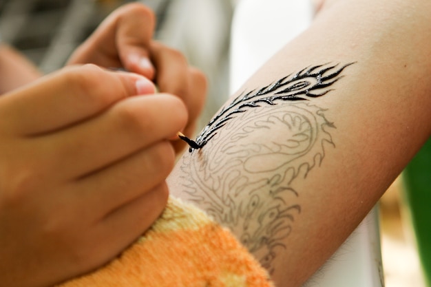 Foto primer artista del tatuaje en el trabajo en el brazo