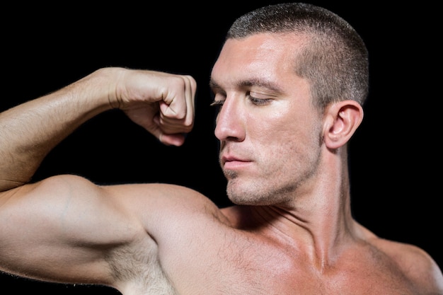 Primer atleta sin camisa serio flexionando los músculos