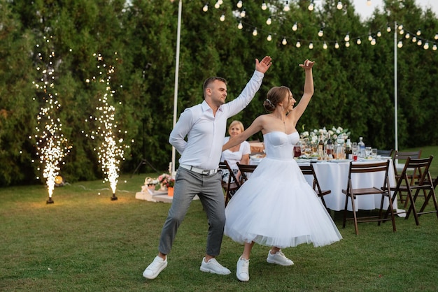 Foto el primer baile del novio y la novia con un vestido de novia corto en un prado verde