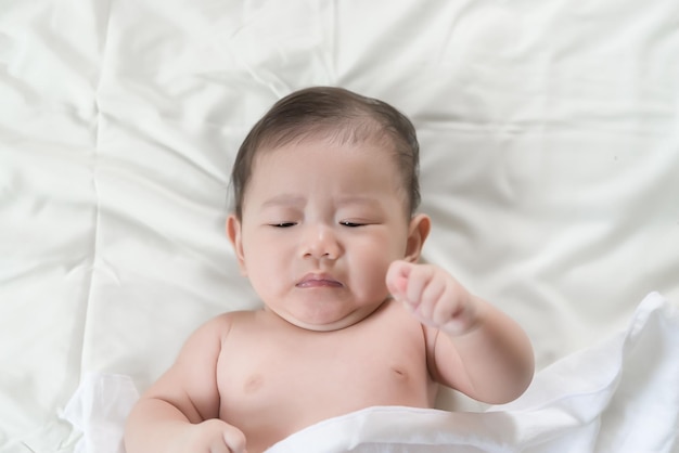 Primer bebé asiático acostado en la cama Linda niña de Tailandia