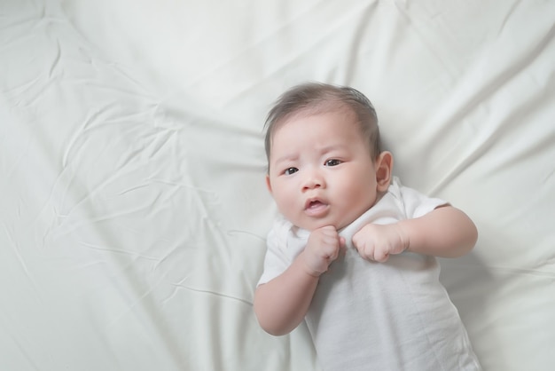 Primer bebé asiático acostado en la cama Linda niña de Tailandia